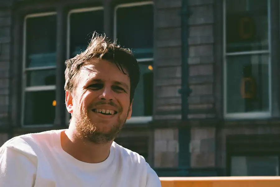 NEKO NEKO smiling in front of a building, wearing a white top