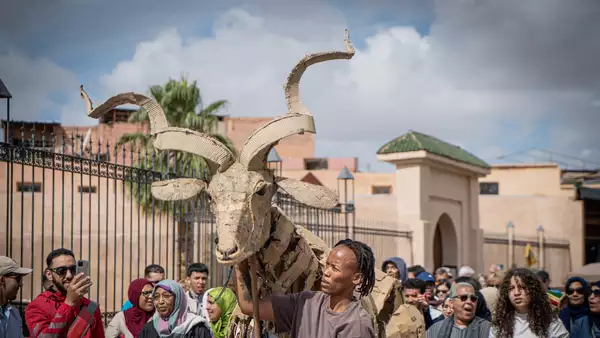 A crowd of people watching a puppet move through the Medina in Marrakesh, Morocco.