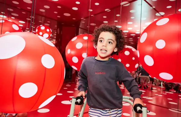 A child plays in a red and white polka dot patterned room by Yayoi Kusama