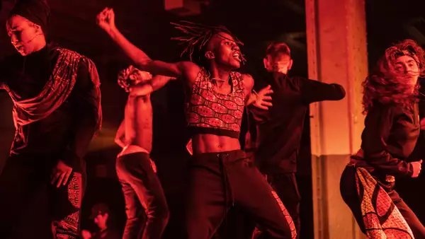 Dancers performing on stage. The image has a red hue.