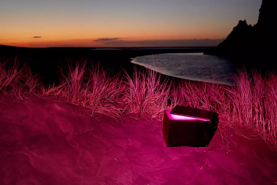 An open capsule on a beach at night. The image has a pink hue.