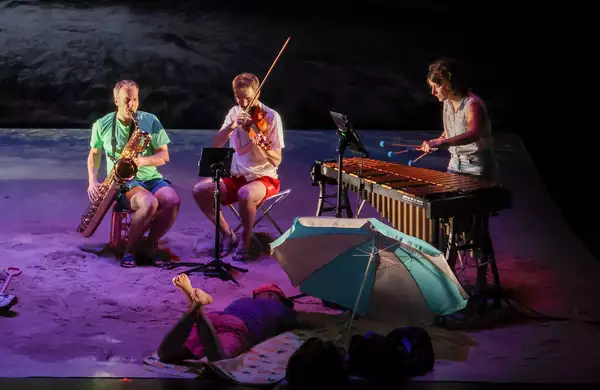 Performers on a beach playing musical instruments