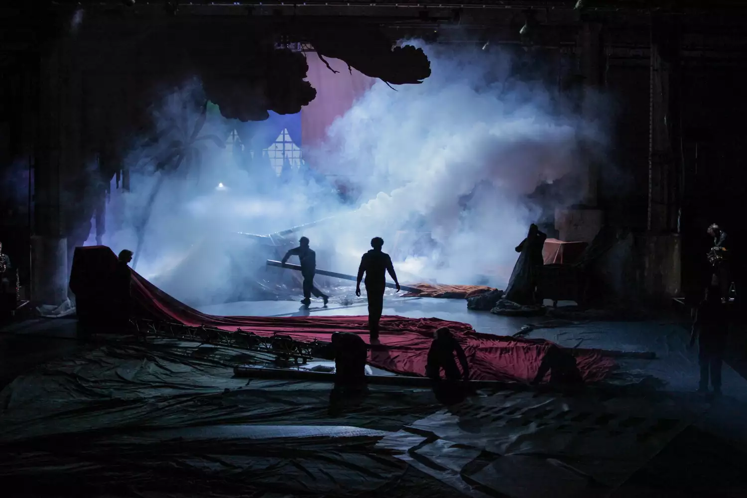 A stage set with silhouettes of people and smoke in the background