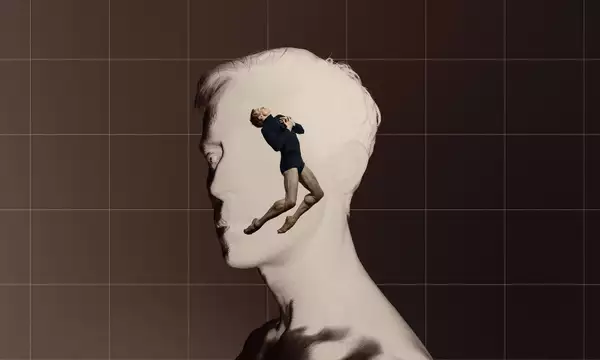 A digital collage features a grayscale side profile of a man's face, with a dancer emerging from within, positioned in a dramatic pose. The background is divided into a warm brown and a grid-like structure, enhancing the contrast between the two figures.