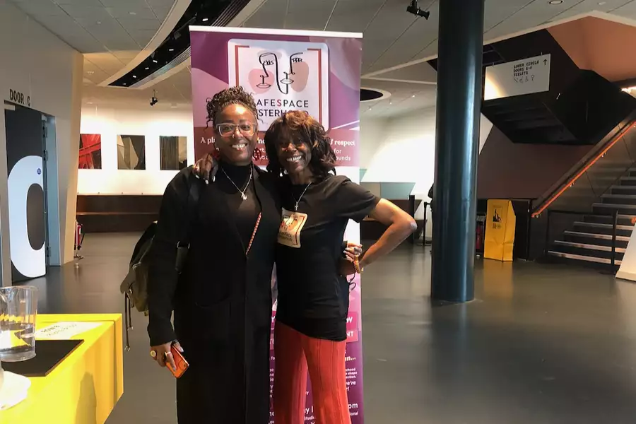 Audrey Hall smiling, hugging and posing of a photo with another person in the Lower Hall Foyer at Aviva Studios