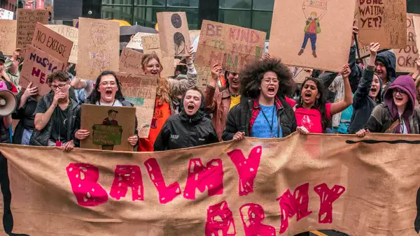 Photograph from a march through Manchester City Centre as part of MIF23. It shows people holding a large banner that reads 'Balmy Army'.