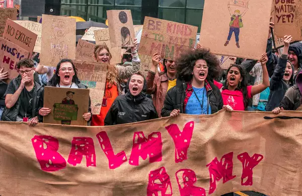 Photograph from a march through Manchester City Centre as part of MIF23. It shows people holding a large banner that reads 'Balmy Army'.