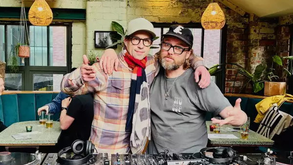 Two members of Chips with Everything smiling behind the decks
