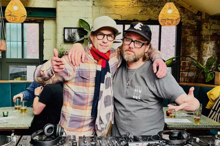 Two members of Chips with Everything smiling behind the decks