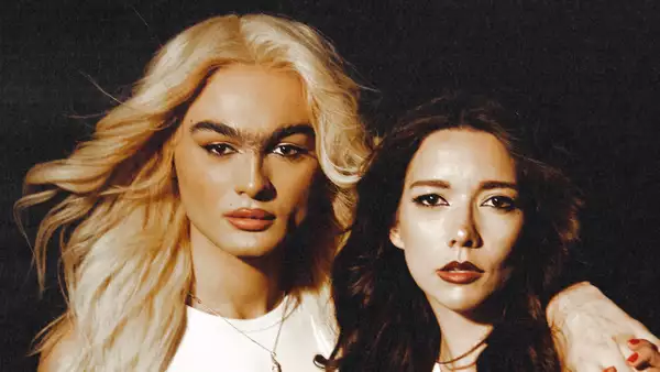Two members of the Darklings with their arms round each other, staring into the camera. Their hair is windswept.