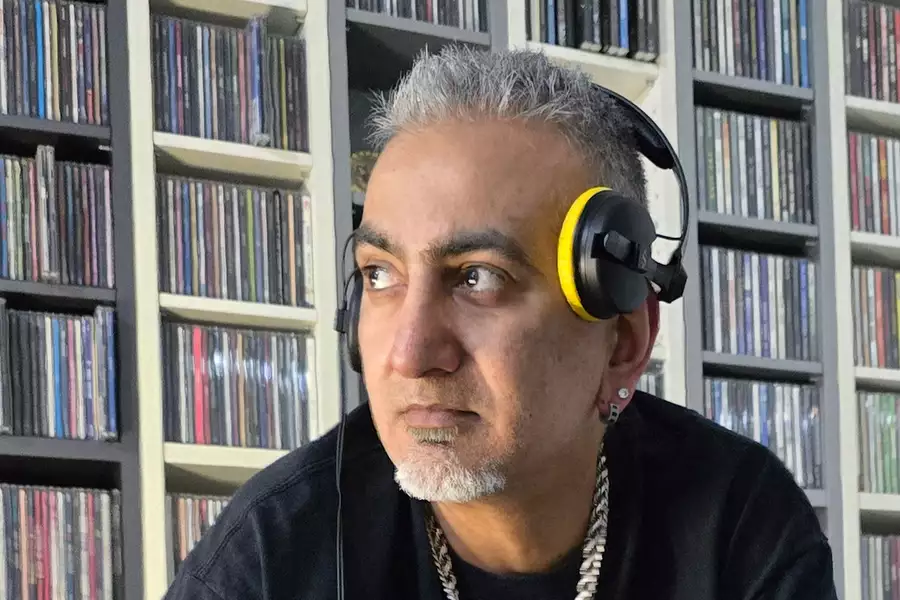 Desi Fusion DJ wearing headphones and stood in front of shelves of records