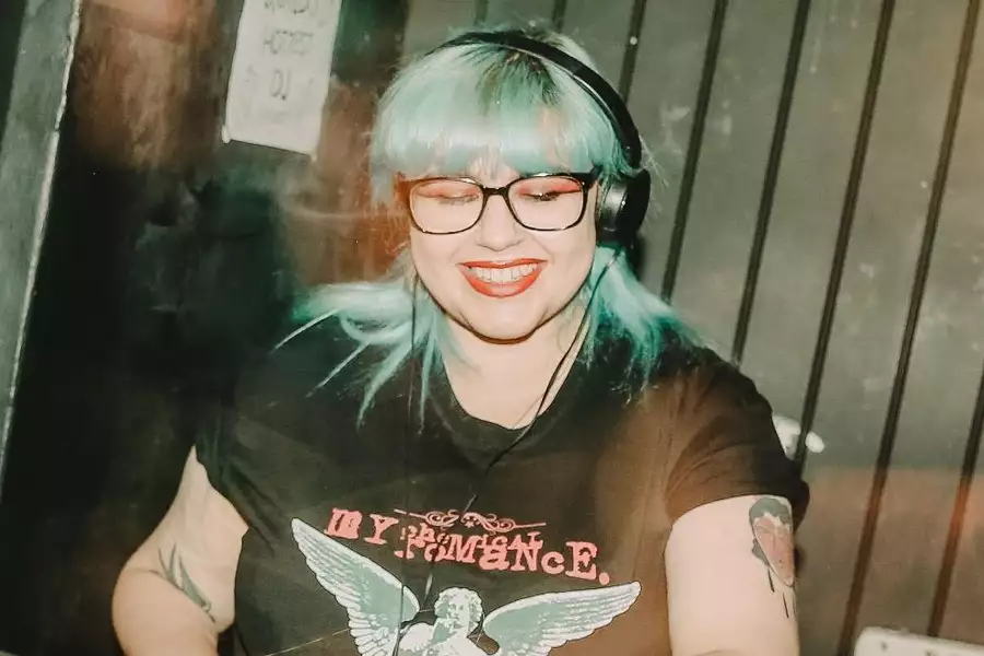Mx World DJing with bright blue hair and wearing a My Chemical Romance t-shirt