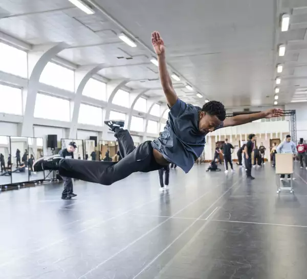 A dancer fully in the air with arms outstretched in rehearsals for Free Your Mind