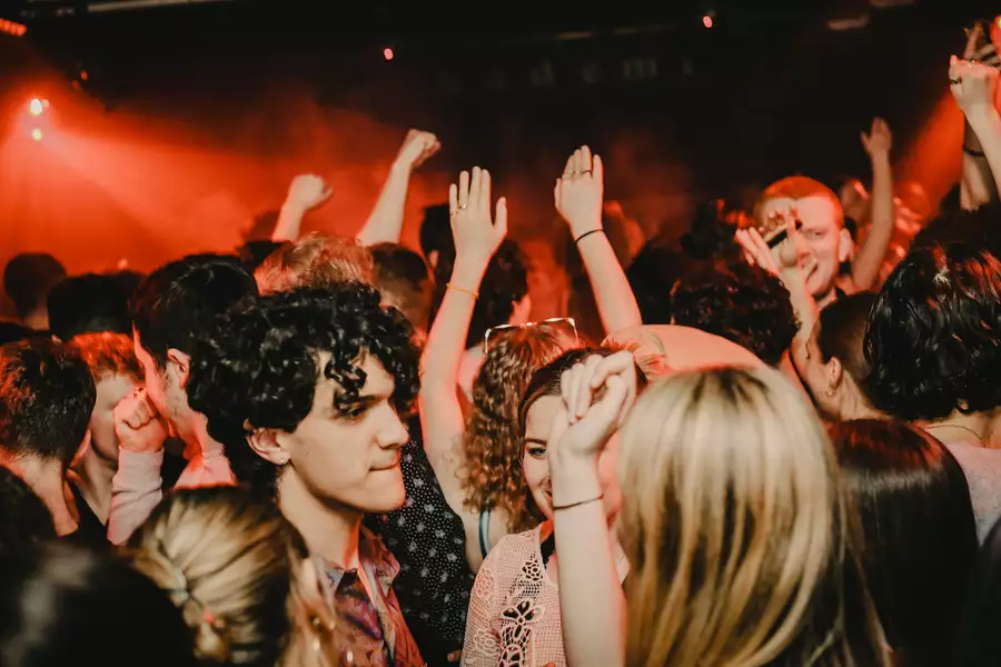 A large crowd of people dancing in a club with red lighting
