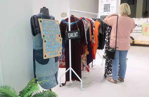Photo of someone browsing a rack of clothing at a clothes swap