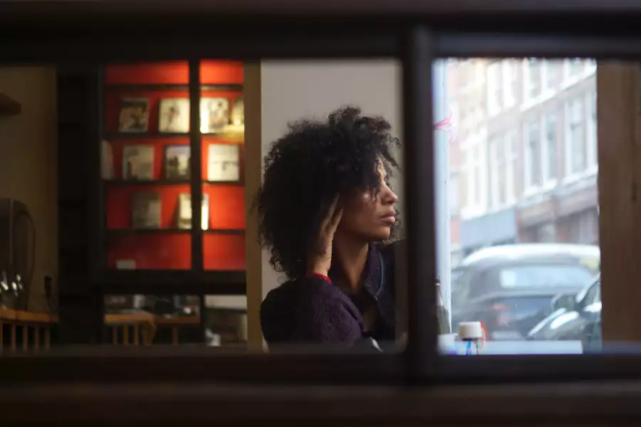 Juliet Ellis inside a dark bar, looking out the window at the street outside.