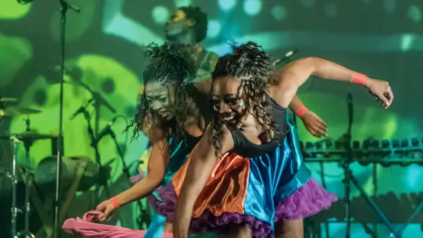 Photo of two dancers on stage dancing with colourful scarves