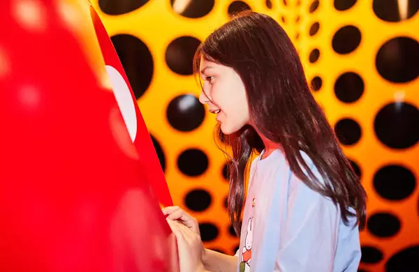 A young girl looks at a Yayoi Kusama artwork