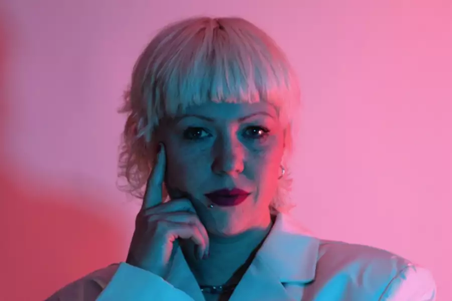 Lois Macdonald in a white suit jacket on a pink background