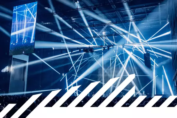 Live musicians on stage with strobe lights and a large crowd