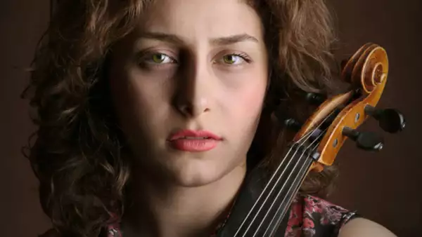 parisa prizadeh looking to camera holding a violin