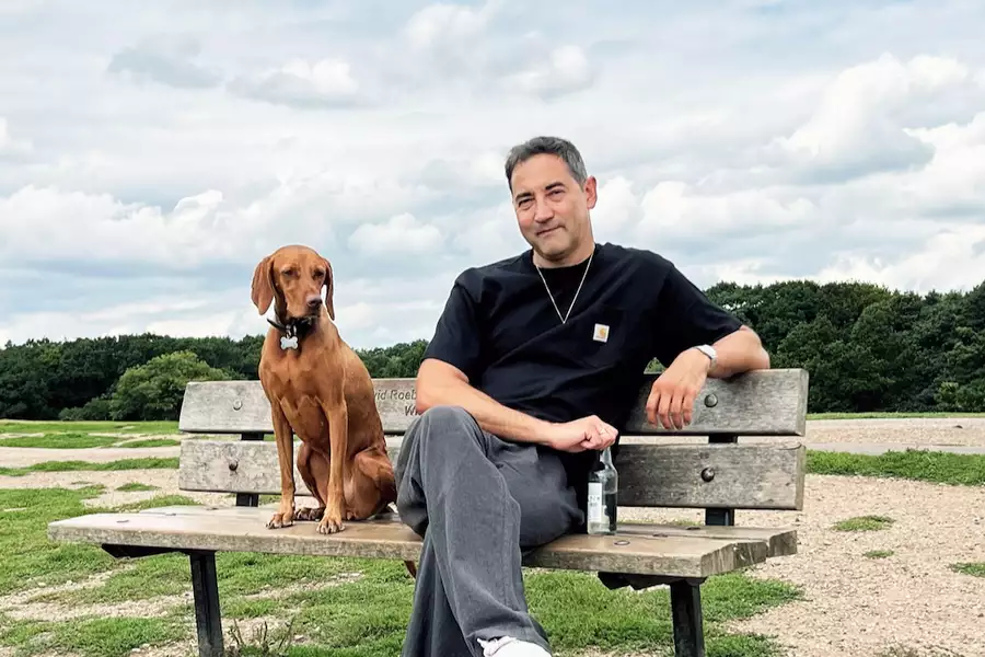 DJ Pipes sat on a bench outside with his dog