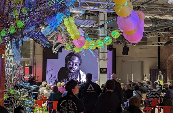 A crowd of people in the Social watching a film on stage