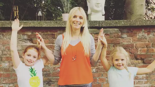 Photo of an adult and two kids practising yoga