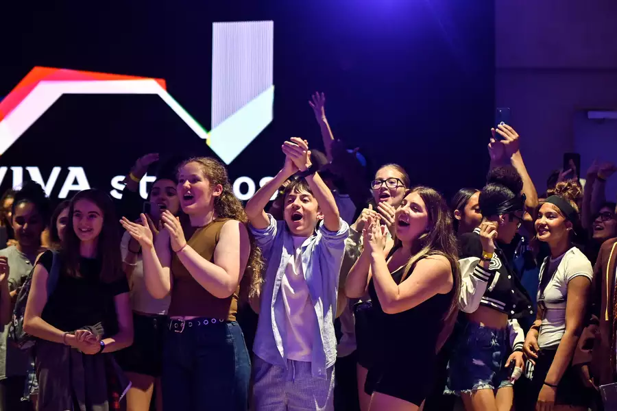 A cheering crowd of young people celebrate enthusiastically in the Social, with a glowing "Aviva Studios" sign in the background.