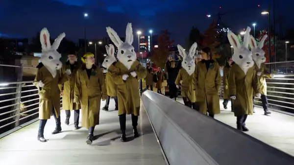 Performers dressed as white rabbits crossing a bridge as part of Free Your Mind