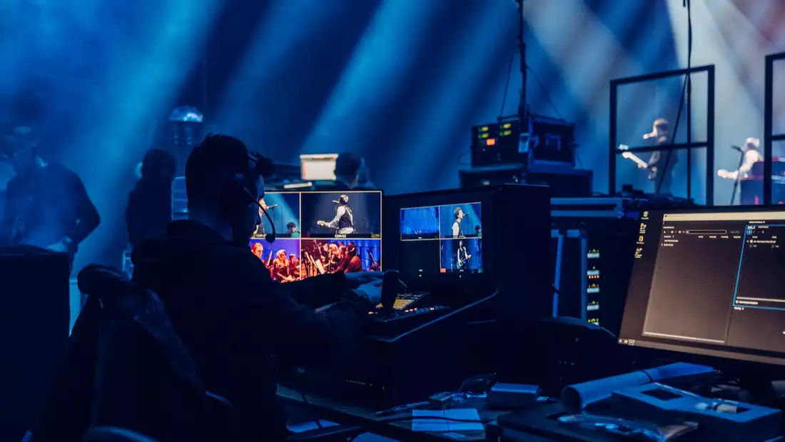 A technician working backstage at the Johnny Marr performance, managing live concert footage on computers.