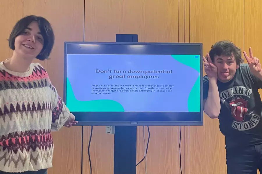 Two people stood in front of a screen which says 'Don't turn down potential great employees'