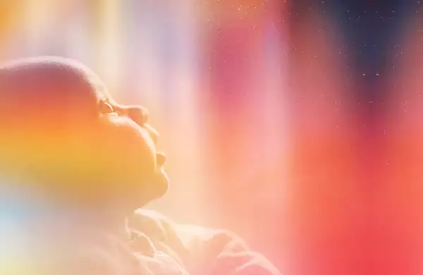 A photograph of a baby staring up in wonder at the night sky