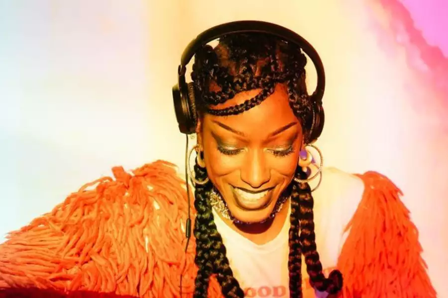 Meme Gold smiling in headphones with a vibrant background.