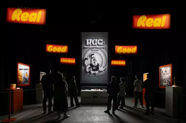 Silhouettes of people in front of a bright room of exhibited art and merchandise