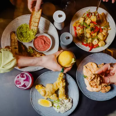 Three people pick small plates with Thai street food